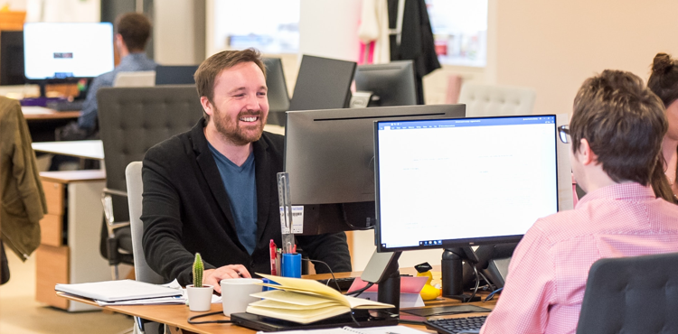 Marketer smiling while working at a desk in a modern office.