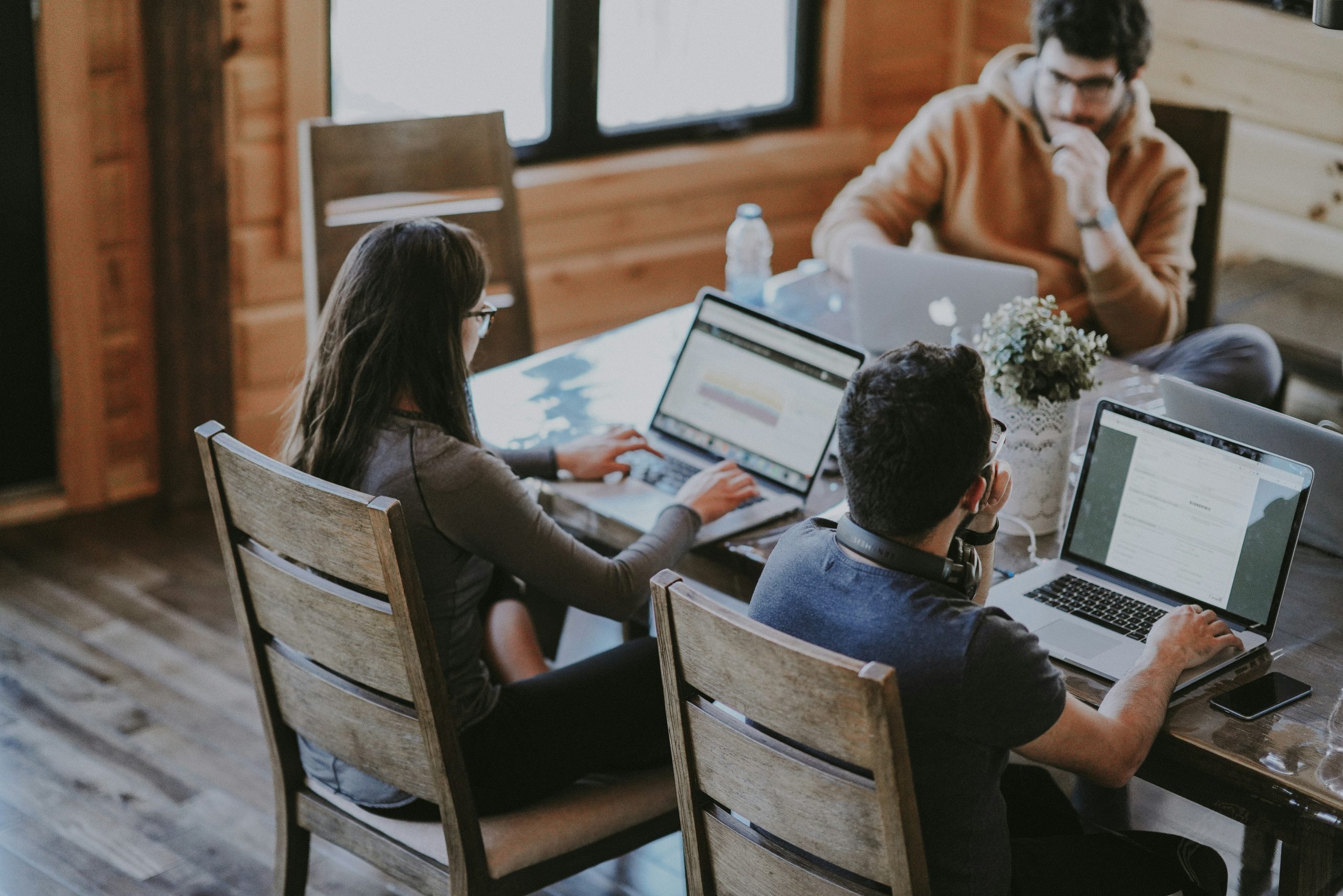 a group of people sitting at a table with laptops